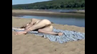 Drunk nude girl lying down on a beach